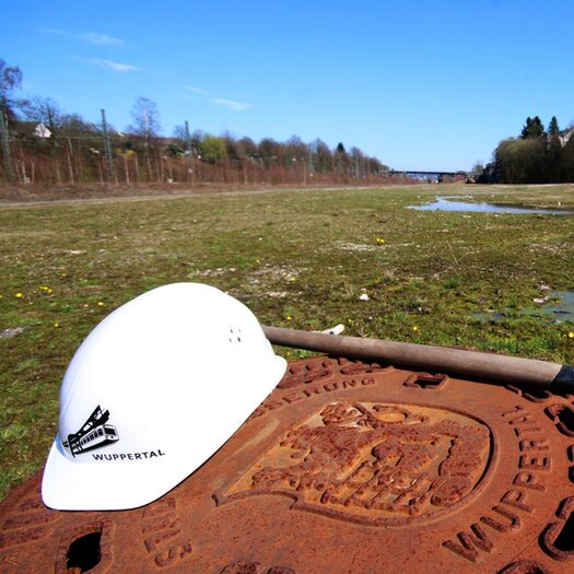 Bauhelm und Schaufel liegen auf einer schlammigen Wiese