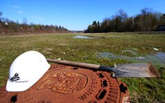 Bauhelm und Schaufel liegen auf einem baureifem Grundstück