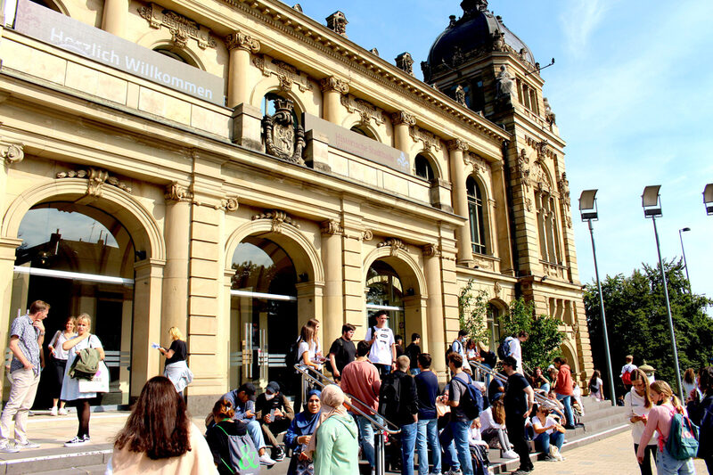 Eine Schülergruppe sitzt auf den Stufen vor der Stadthalle