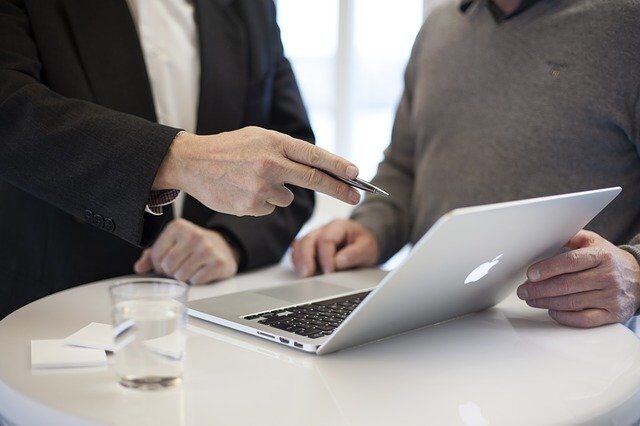 Zwei Männer sehen sich gemeinsam etwas auf dem Bildschirm eines Laptops an.