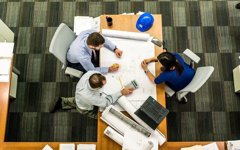 Drei Personen arbeiten gemeinsam an Planungsunterlagen.