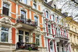 Altbaufassade mit Stuck an den Fenstern und geschmiedeten Balkongeländern.