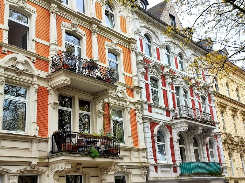 Altbaufassade mit Stuck an den Fenstern und geschmiedeten Balkongeländern.