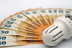 Geldscheine liegen um ein Heizungsthermostat herum