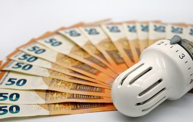 Geldscheine liegen um ein Heizungsthermostat herum