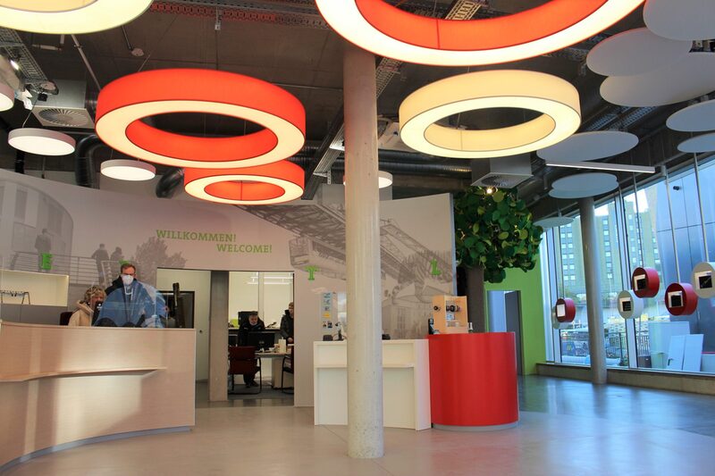 Der Pavillon von innen mit großem Infotresen und bunten Lampen unter der Decke.