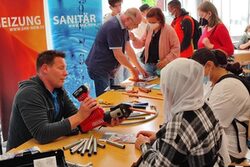 Am Stand der Innung für Heizung, Sanitär und Klima lernen Schülerinnen, wie man Rohre verbindet.