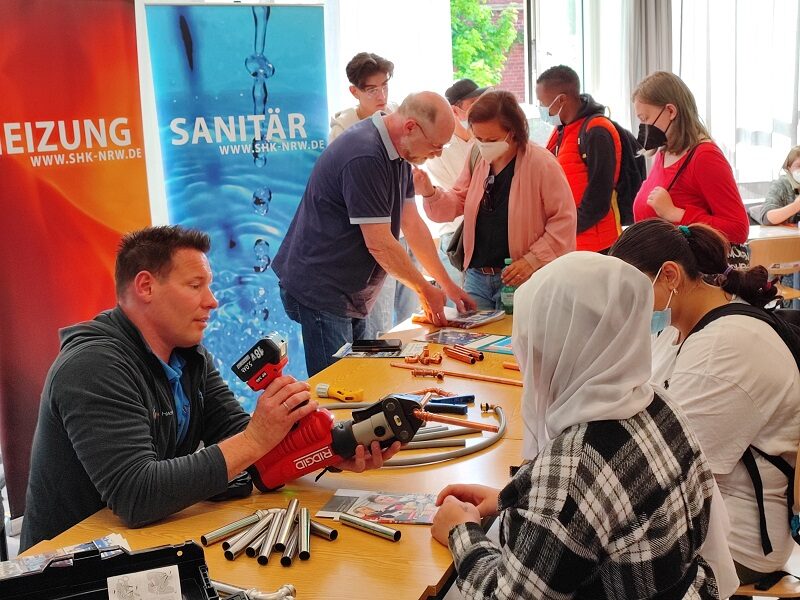 Am Stand der Innung für Heizung, Sanitär und Klima lernen Schülerinnen, wie man Rohre verbindet.