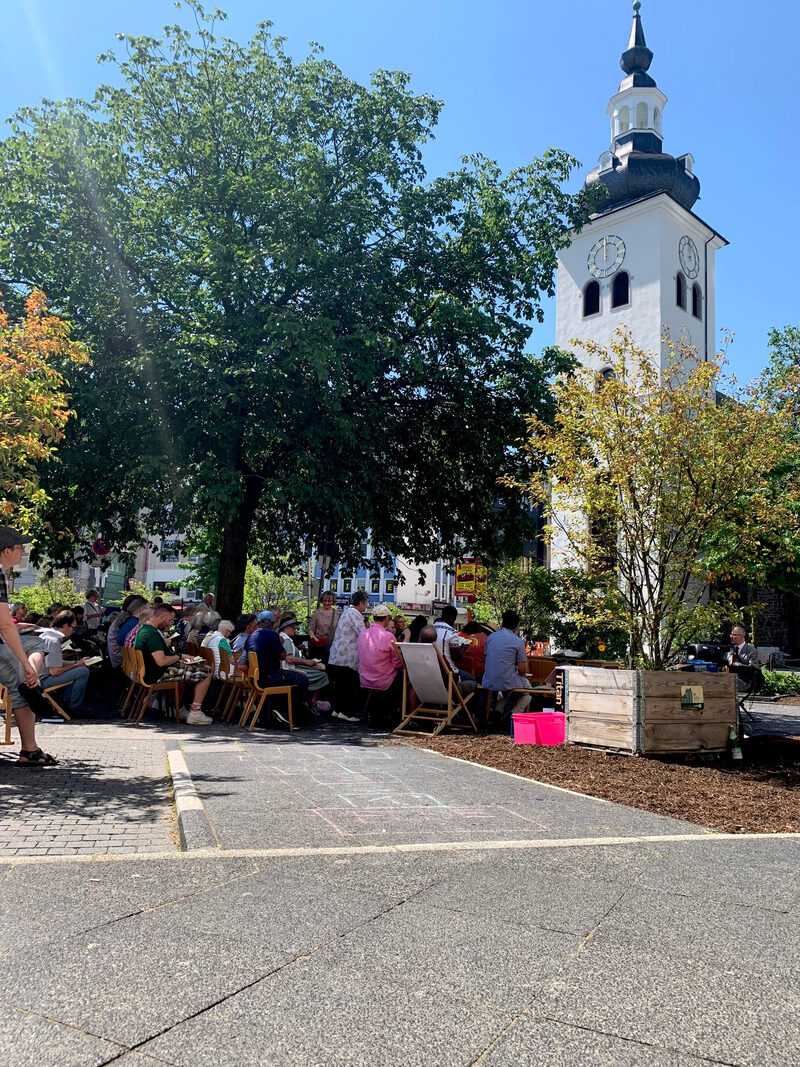 Eine Gruppe Menschen hält einen Open-Air-Gottesdienst auf dem Platz am Kolk ab.