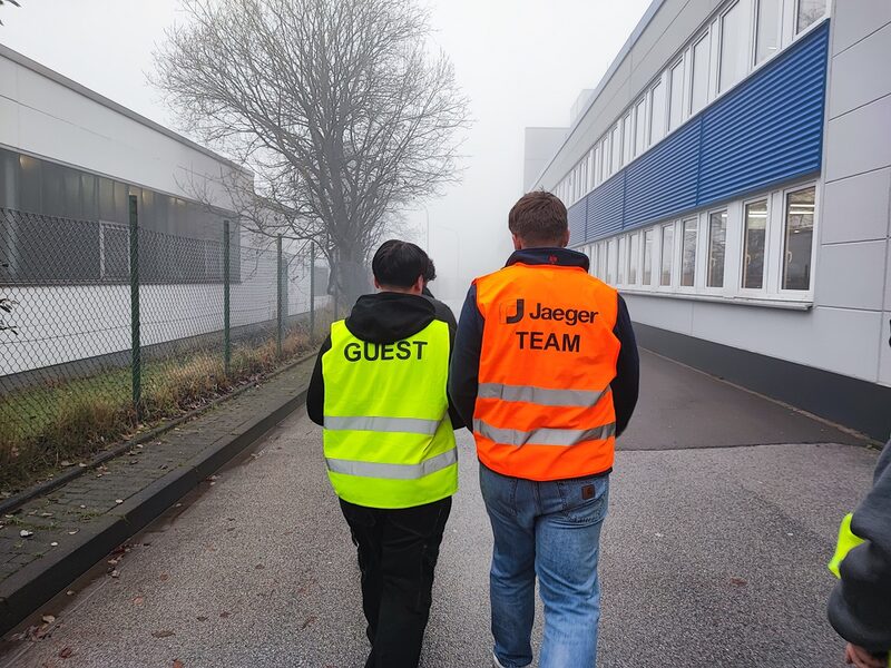 Ein Azubi mit Warnweste und der Aufschrift Jaeger-Team und einem Schüler mit Warnweste und der Aufschrift Gast.