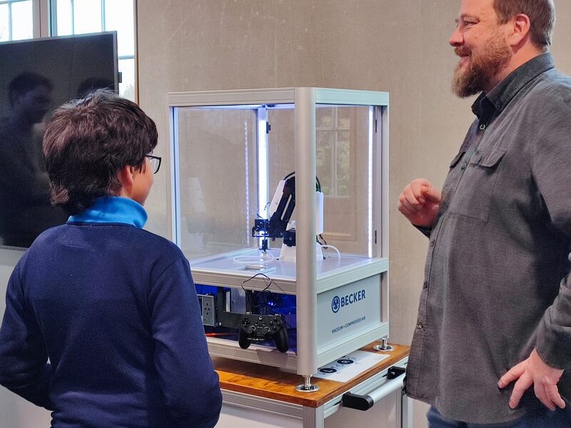 Ein Schüler steht vor einem Roboterarm.