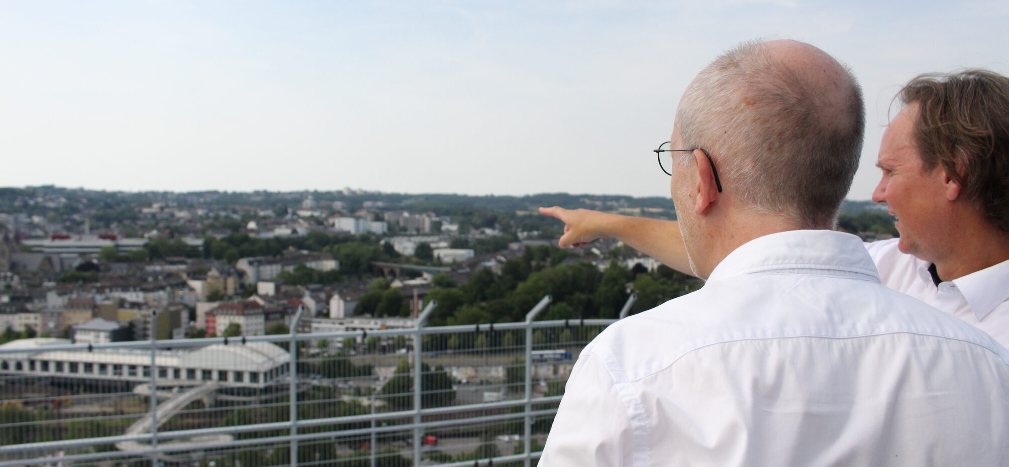 Zwei Männer auf dem Dach des Gaskessels Heckinghausen blicken hinunter auf die Stadt.